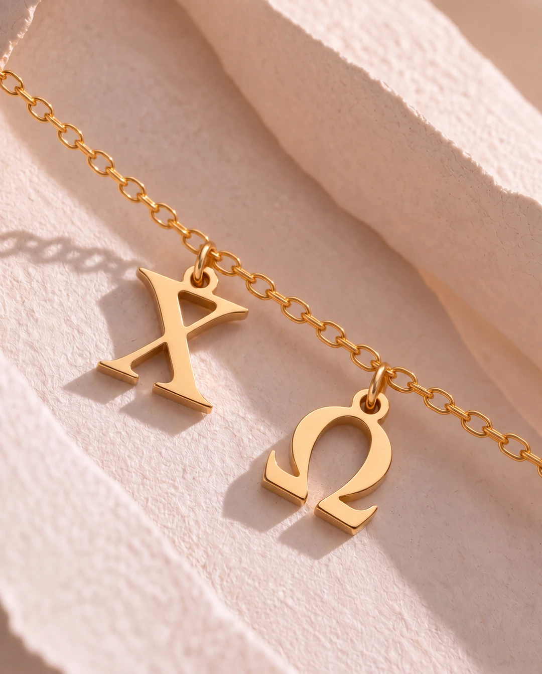 Chi Omega gold letter pendants on sculpted blush paper
